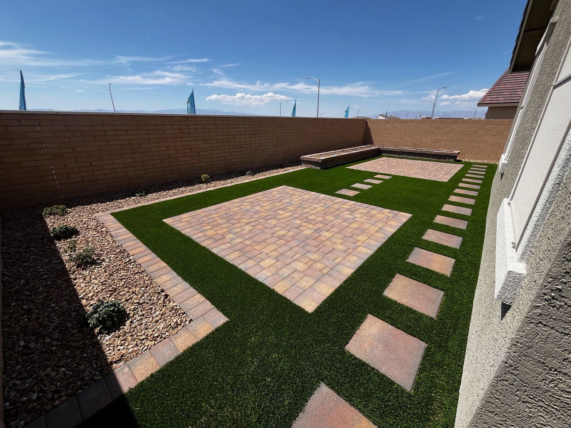 A backyard with a brick walkway and a lush green lawn.