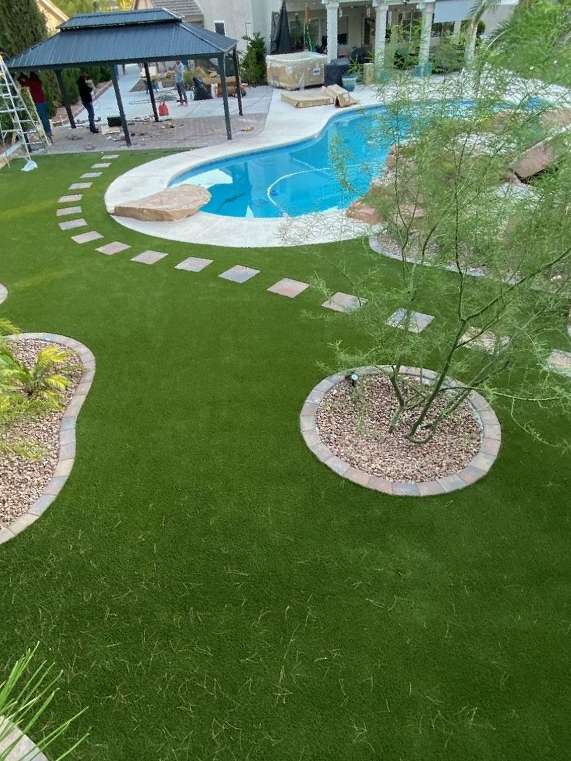 An aerial view of a backyard with a swimming pool and a lush green lawn.