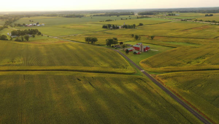 An aerial view of a farm surrounded by fields and a road.