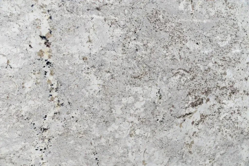 Close-up of light gray, speckled stone or concrete surface with a rough texture