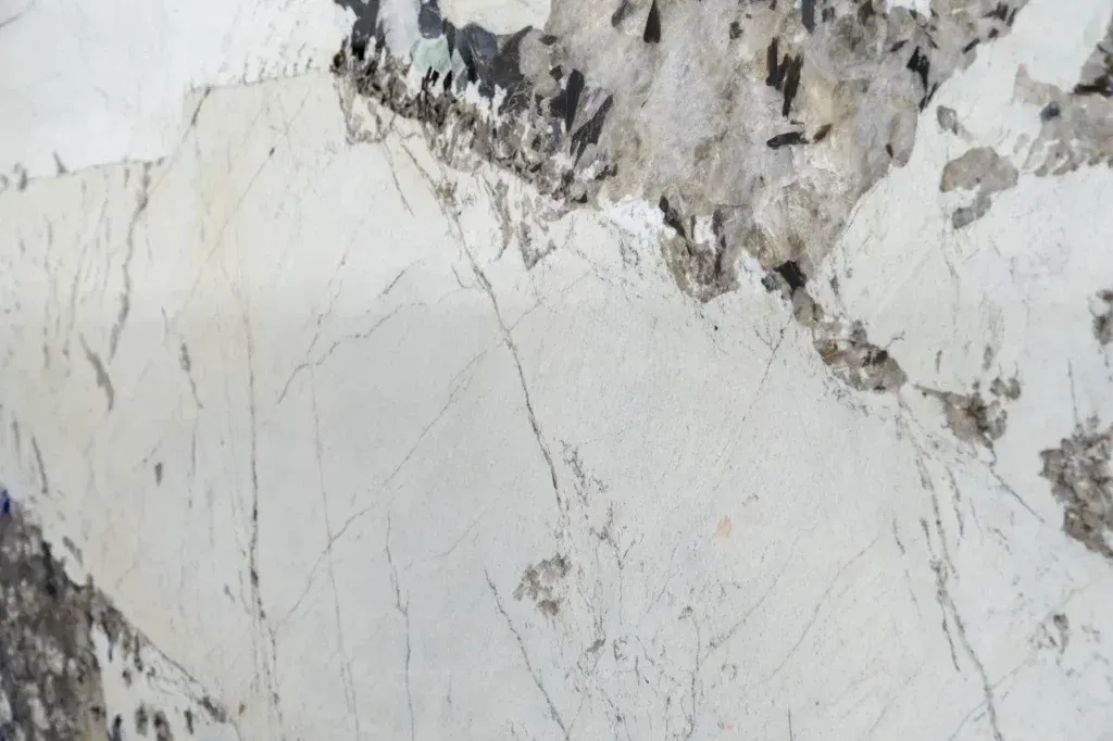 Close-up of a white and gray marble surface with dark veining and rough patches