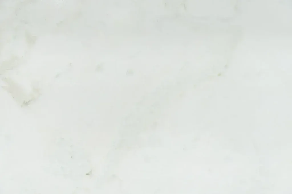 Plain white surface with faint gray smudges and small specks