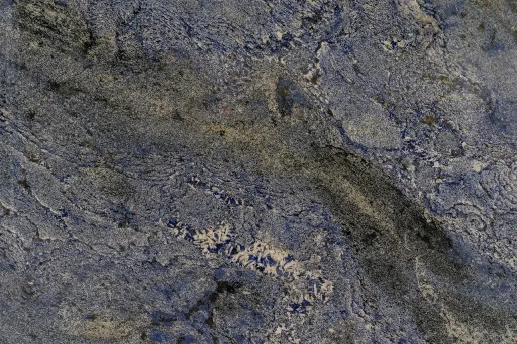 Close-up of rough gray and blue rock or concrete surface with a dark diagonal crack