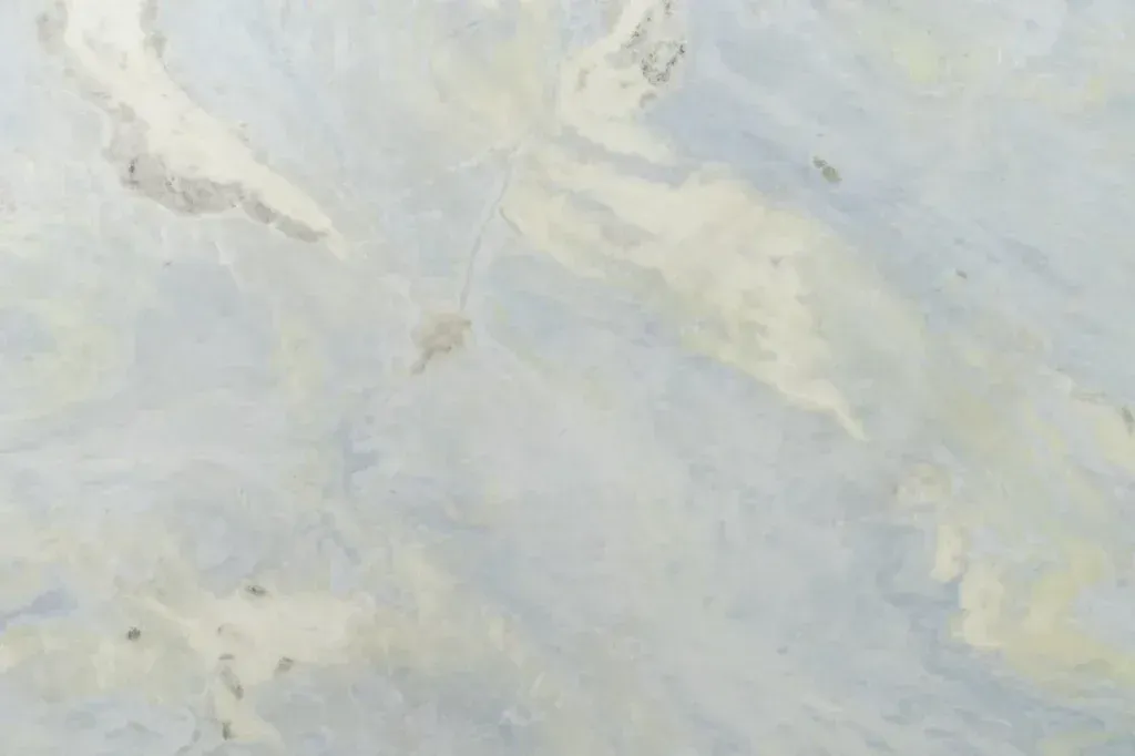 Abstract pale blue and cream marble-like texture with soft, cloudy streaks