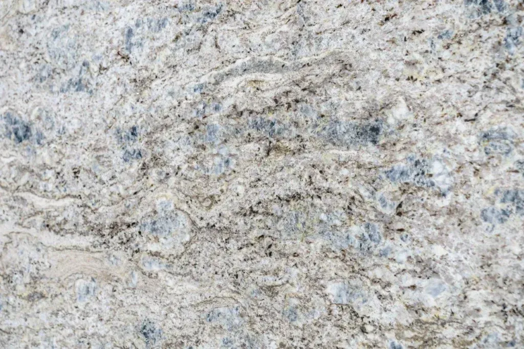Close-up of a light gray and beige speckled stone surface with rough texture