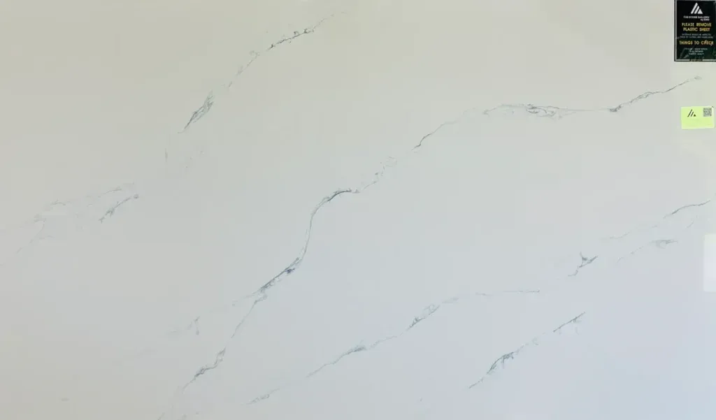 Light beige marble-like wall with faint gray veining and small labels in the top-right corner