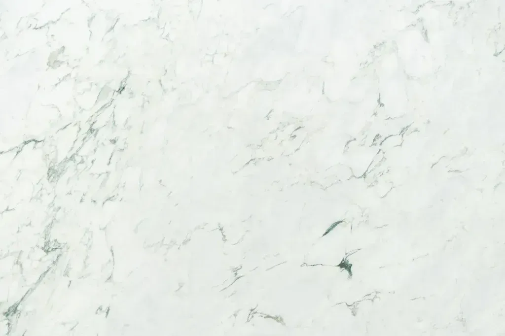 White marble surface with subtle gray veining and faint greenish marks
