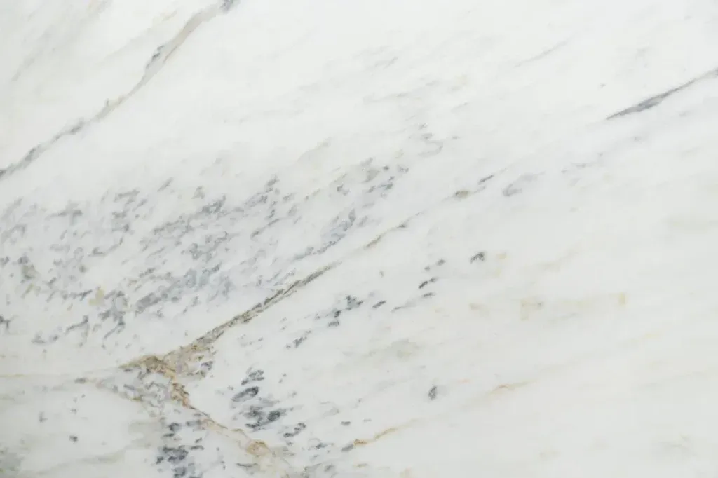 White marble surface with subtle gray veining and a small beige streak near the bottom left