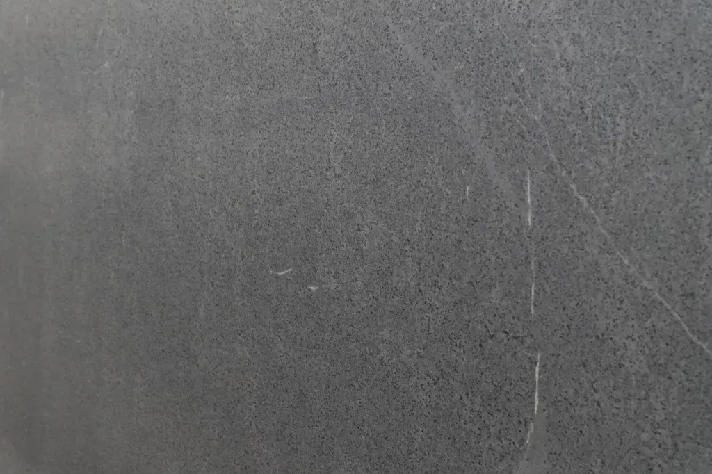Gray textured wall with faint vertical and diagonal cracks