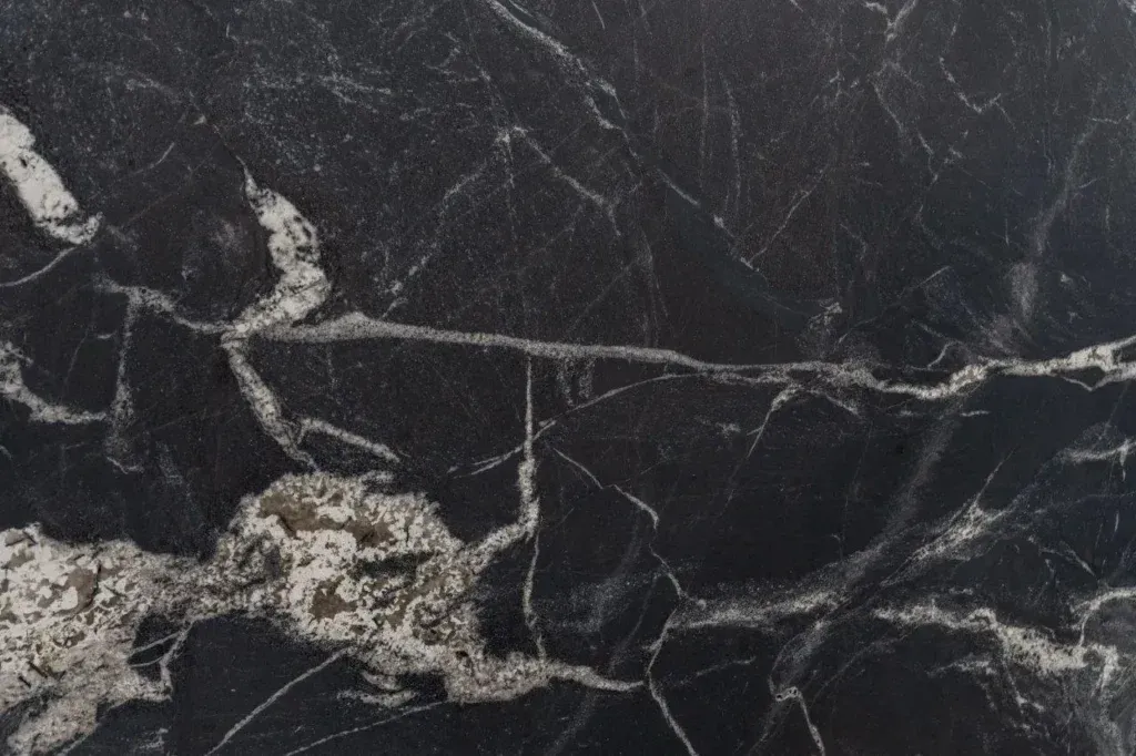 Dark black marble surface with thin white veining and light gray patches