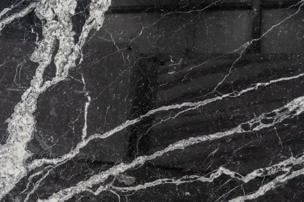 Black marble-like stone surface with white veins running diagonally