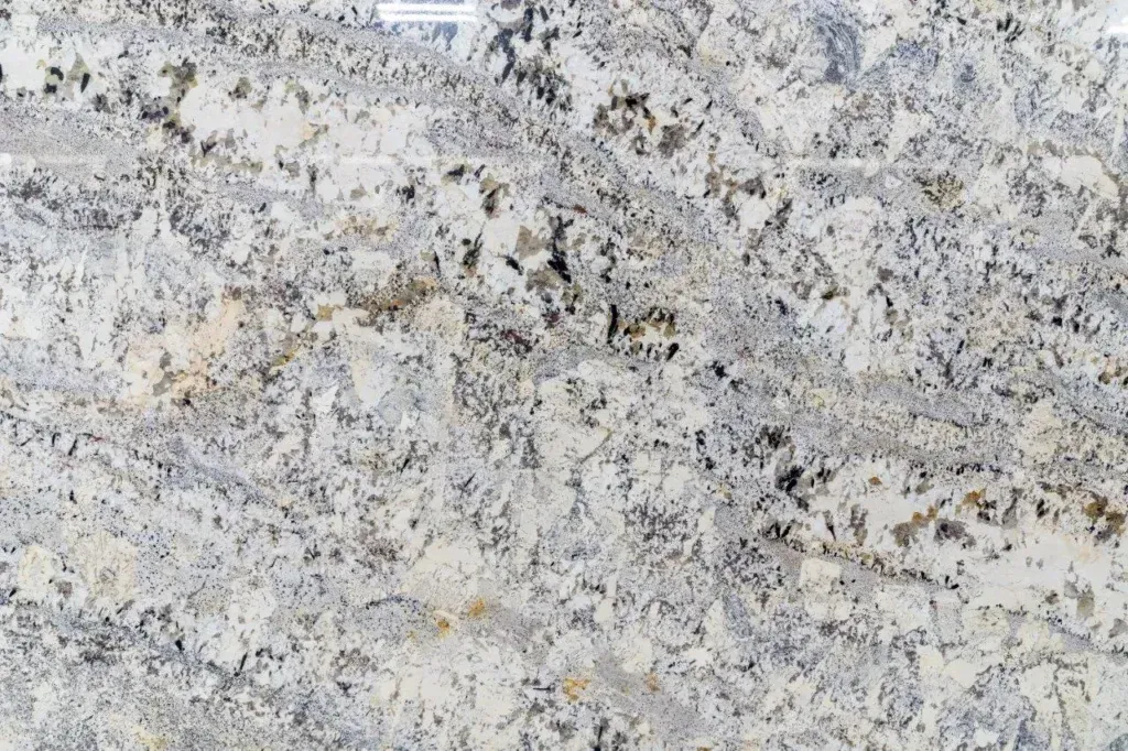 Close-up of a light gray and beige speckled stone or granite surface with dark flecks