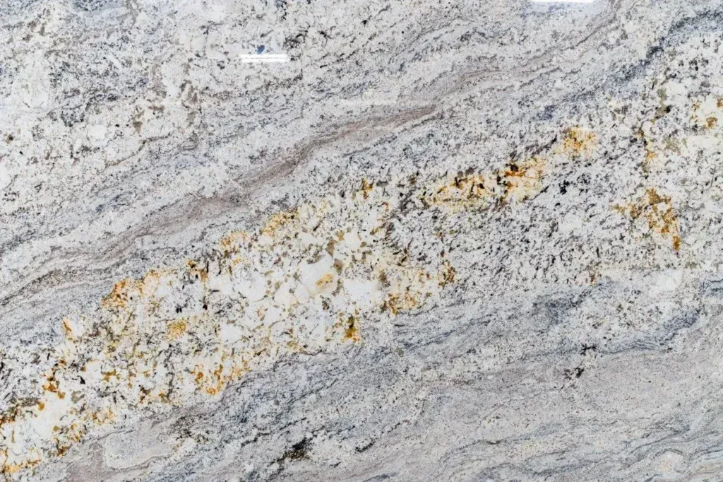 Close-up of light gray granite with wavy white, black, and yellow mineral streaks