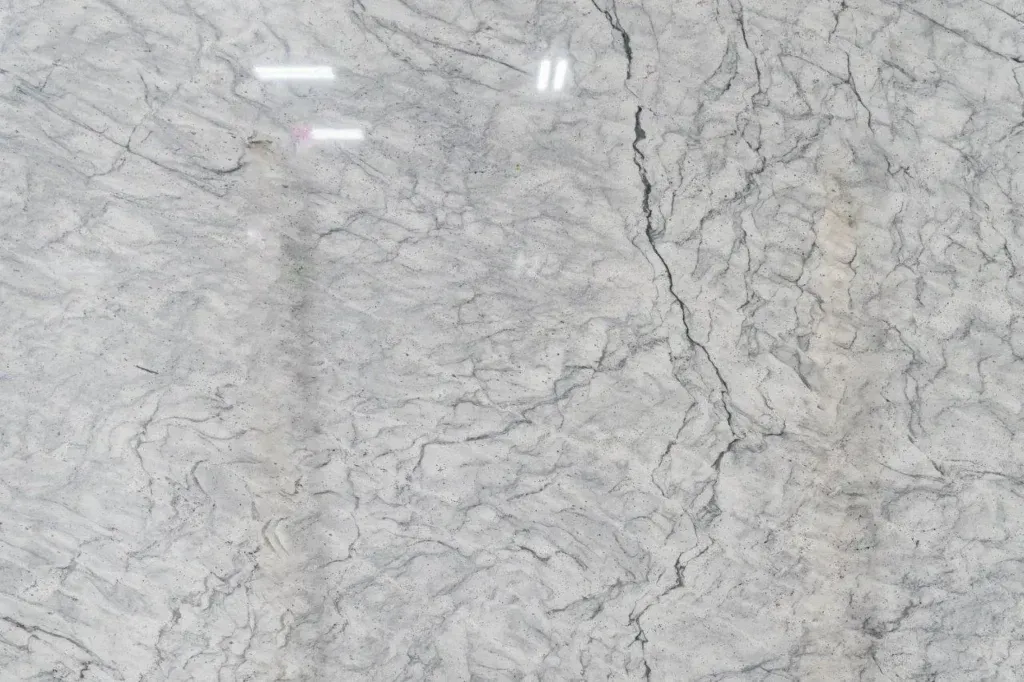 Light gray marble surface with subtle dark veining and reflections of overhead lights