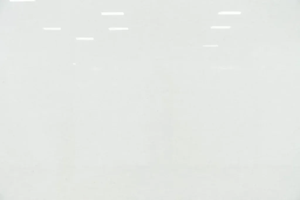 Blank white surface with faint reflections of overhead lights near the top