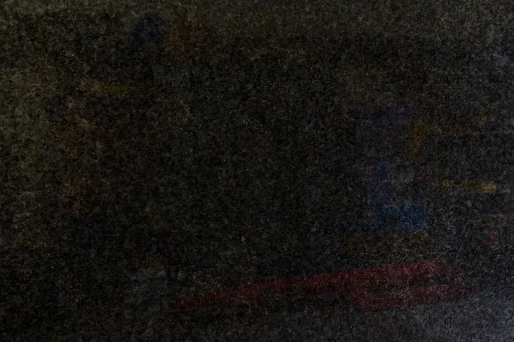 Dark, grainy scene with a red car parked in low light near a building.