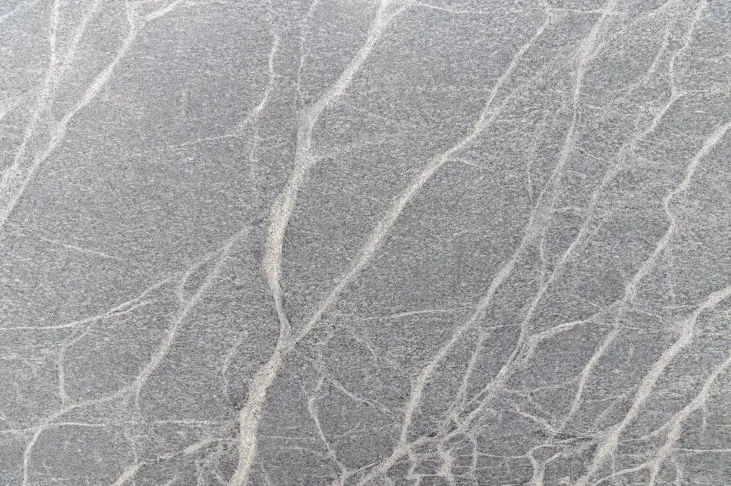 Gray marble-like surface with fine white veins and a textured pattern