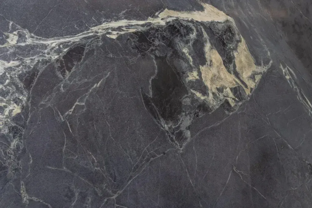 Dark gray marble surface with white veining and beige patches