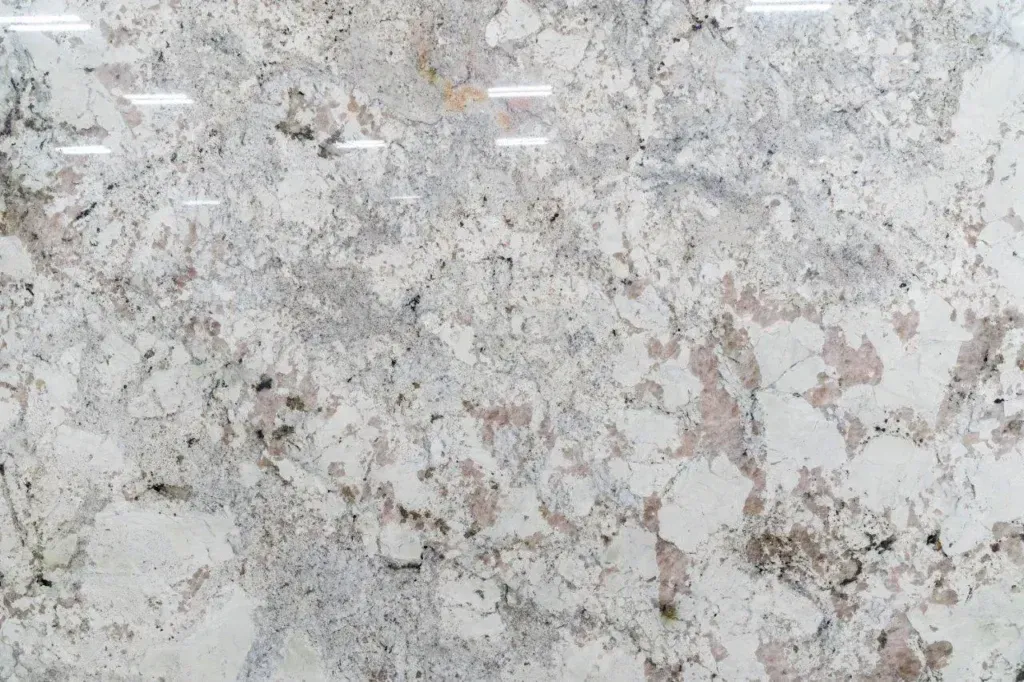 Close-up of a light gray and beige speckled stone or marble surface with a rough texture