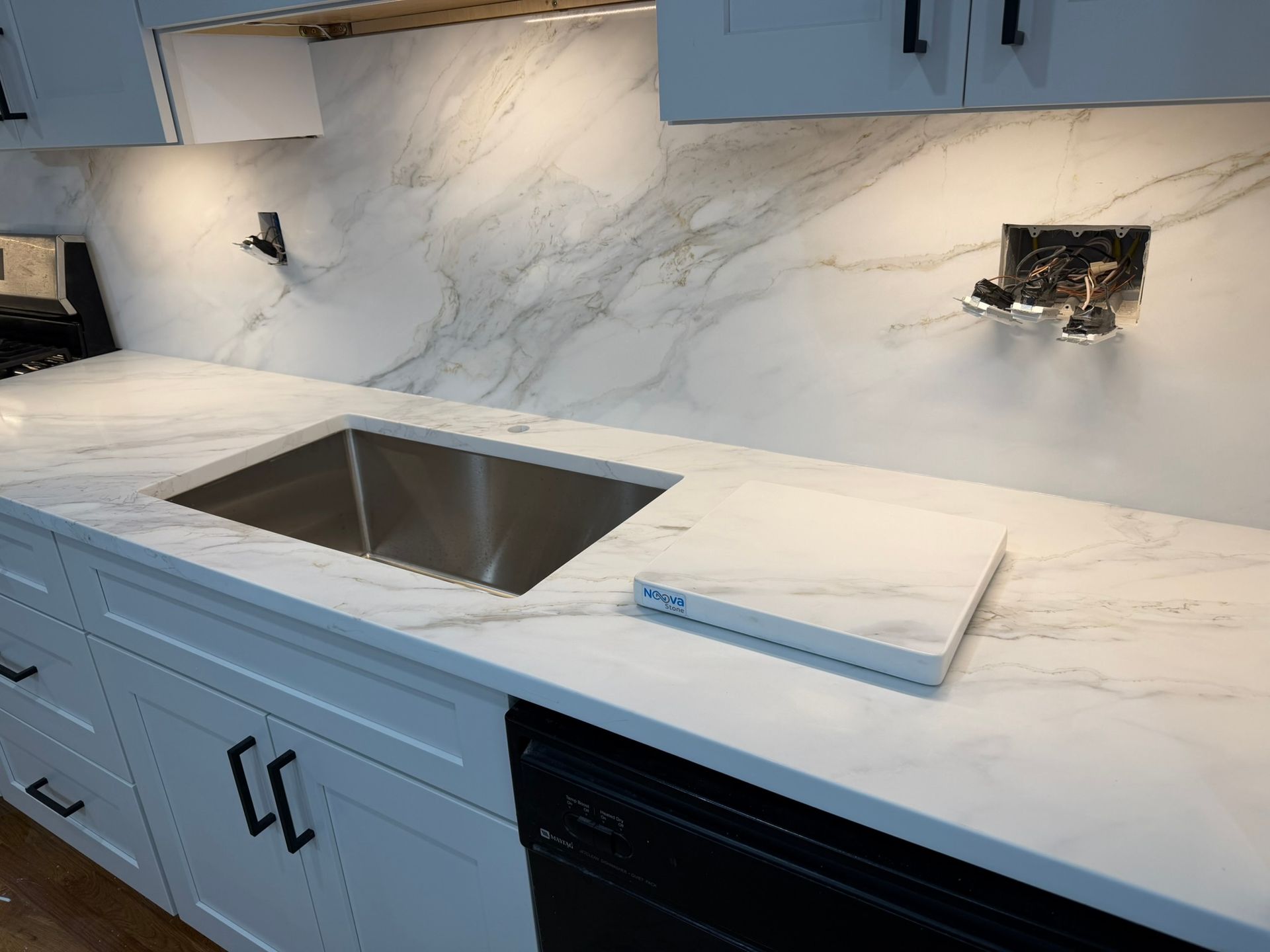 White marble kitchen countertop with an undermount sink and blue-gray cabinets under construction