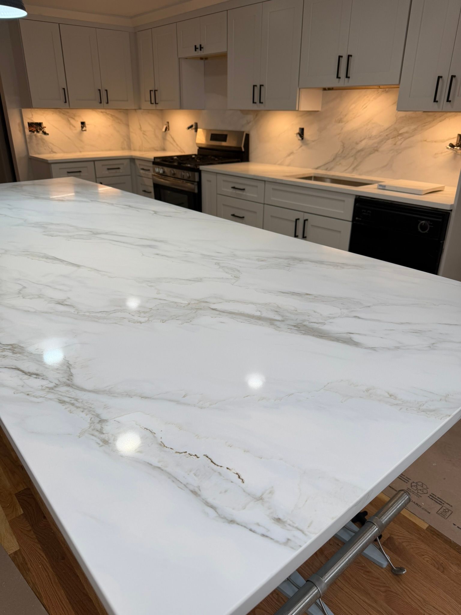White marble kitchen island with gray veining in a modern white kitchen