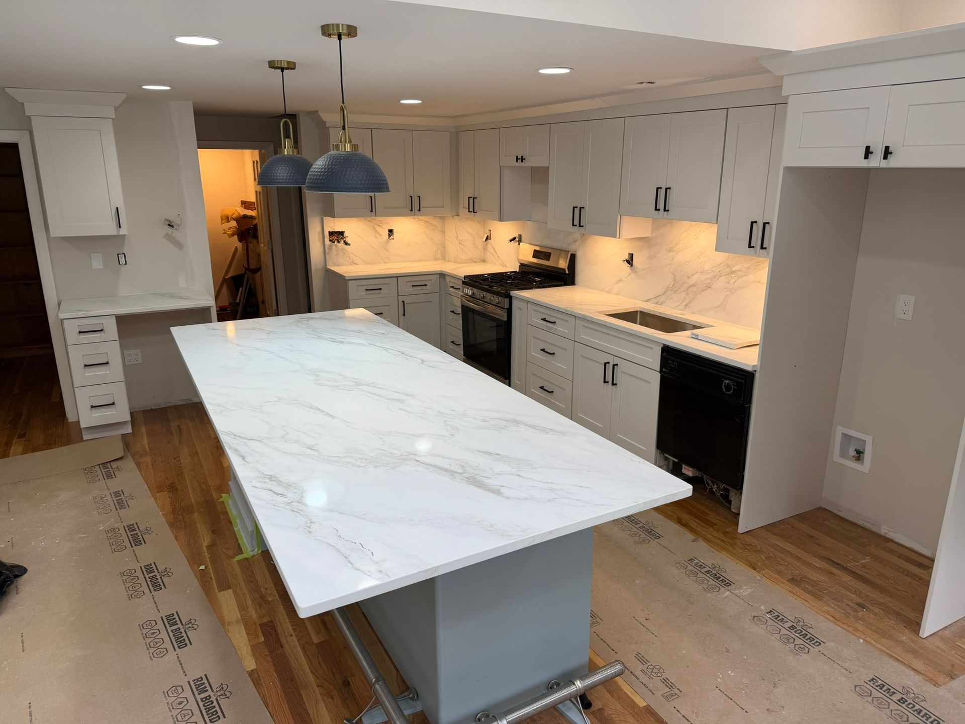 Bright kitchen with white cabinets, marble island, and blue pendant lights