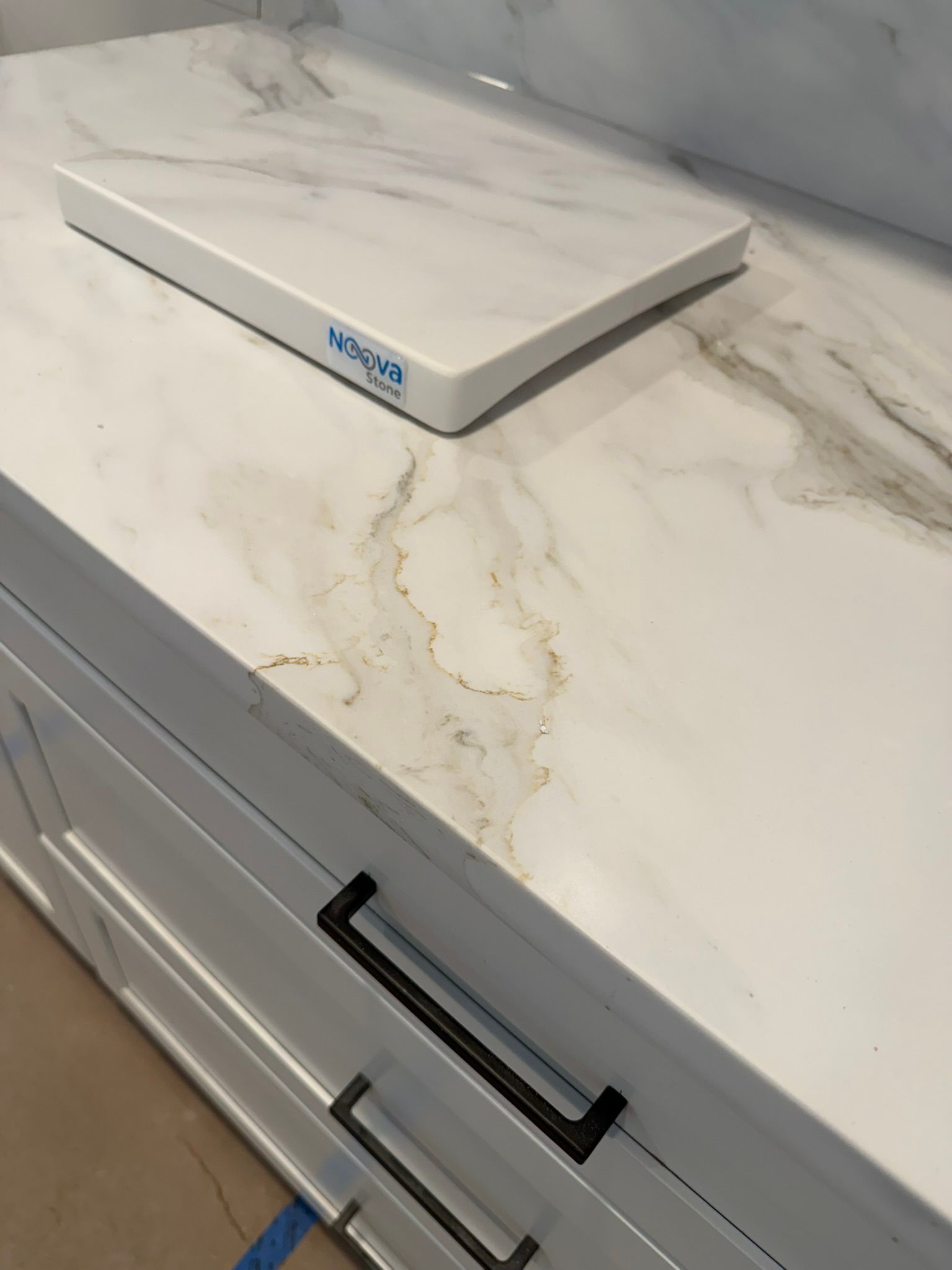 White marble-look countertop with a small white box on top and a cabinet drawer below