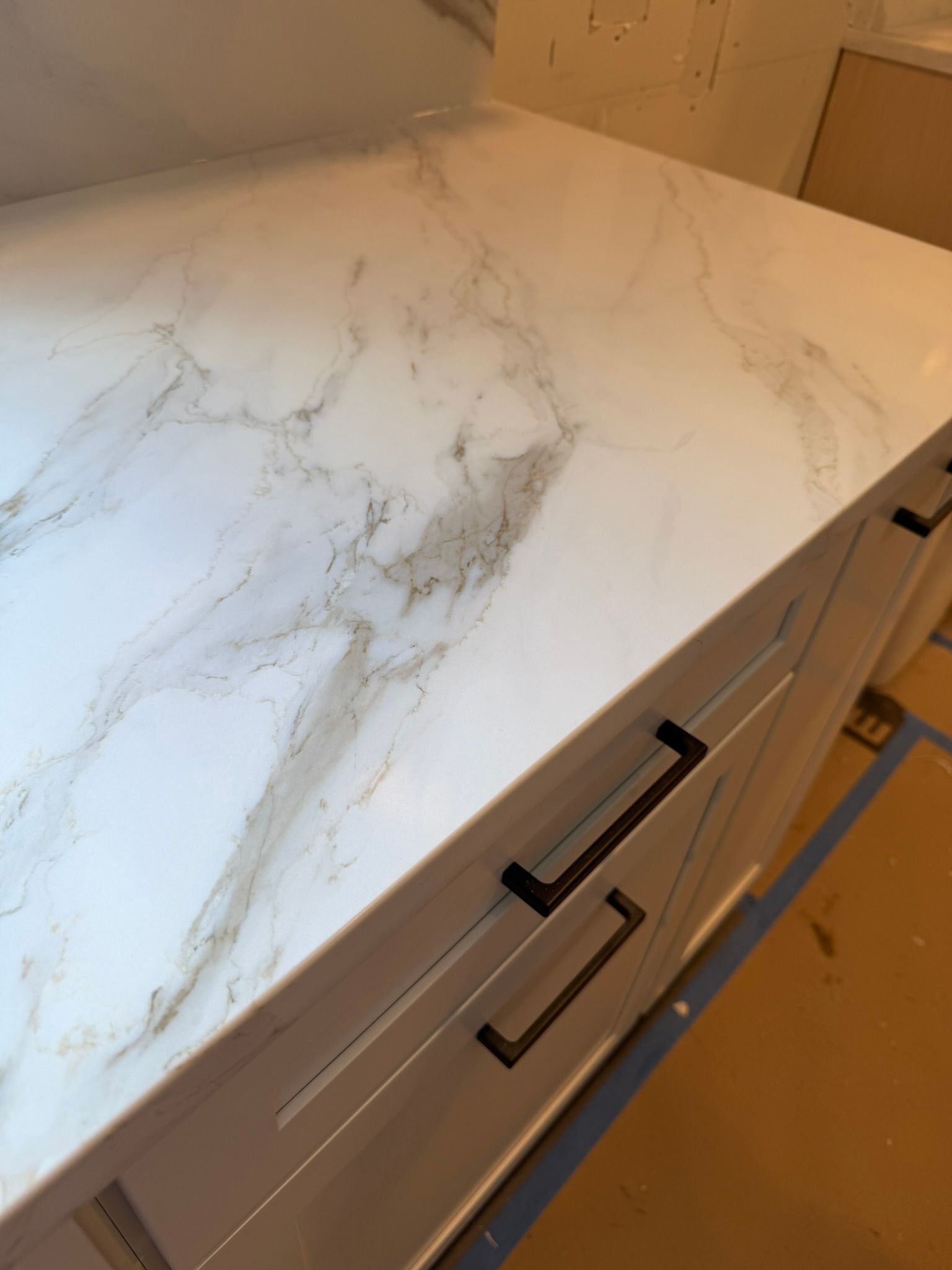 White marble-look countertop with gray veining and black drawer handles in a kitchen cabinet area