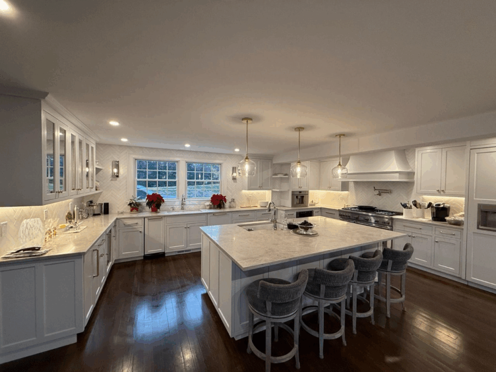 Bright modern white kitchen with a large island, bar stools, and dark wood floors