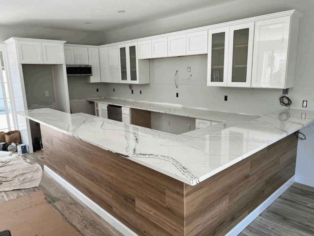 Bright modern kitchen with white cabinets, marble island, and wood-paneled base cabinets