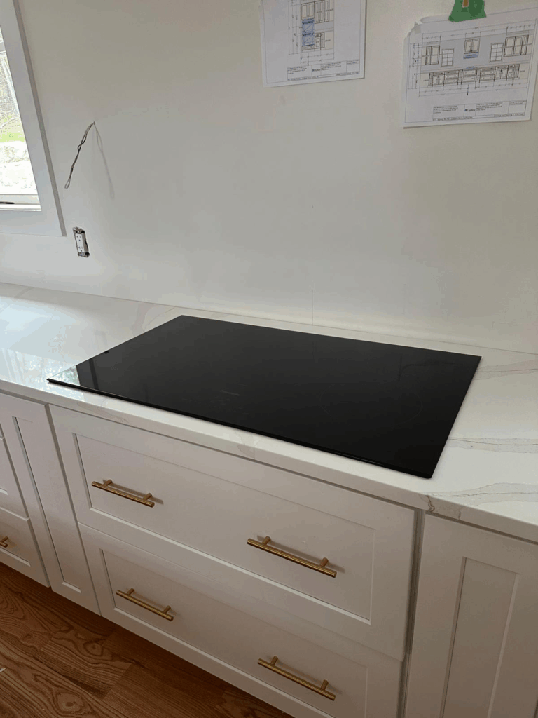 White kitchen counter with a black induction cooktop and drawers below