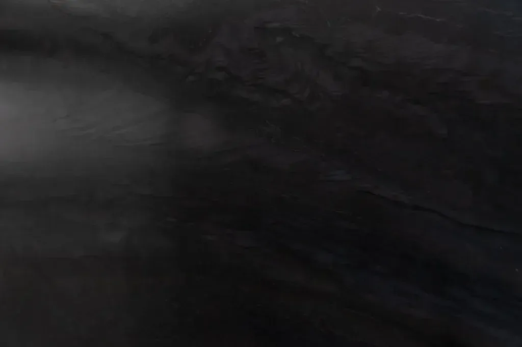Dark, blurry close-up of a black surface with faint gray streaks
