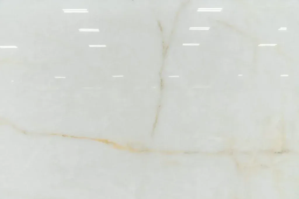 White marble surface with subtle gray and gold veins and faint reflections