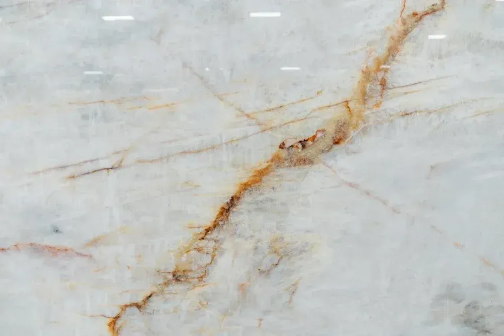 Light gray marble surface with a diagonal golden-brown vein