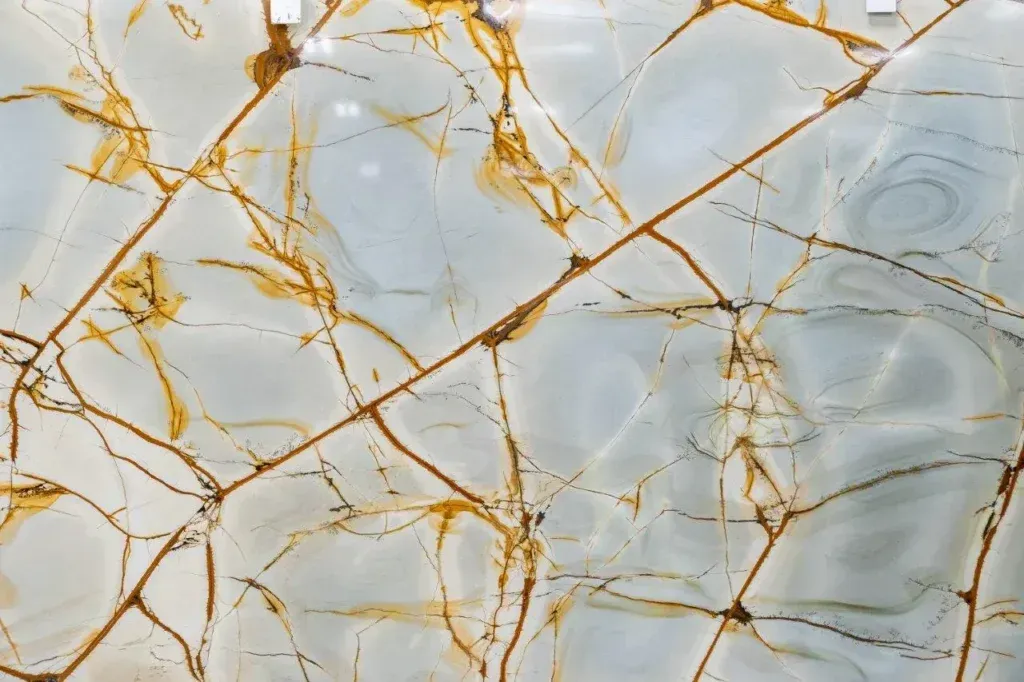 White marble surface with gold veining and gray swirls, like a polished stone pattern