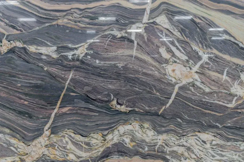 Gray and cream veined stone surface with layered, wavy patterns and thin white cracks