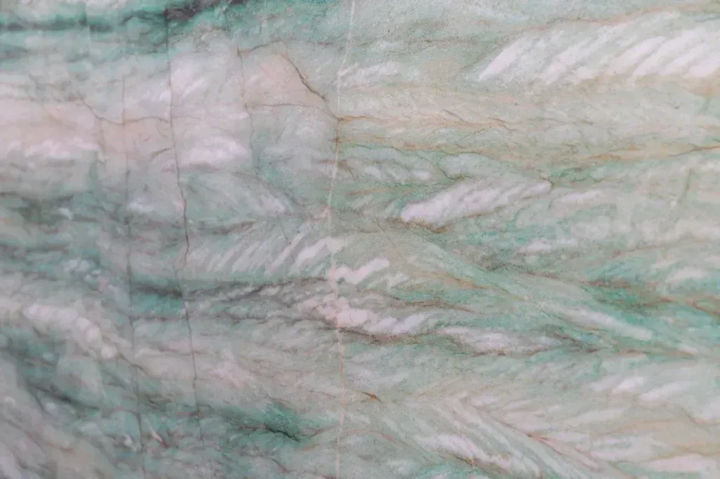 Close-up of pale green and white marbled stone with soft veining and cloudy patterns