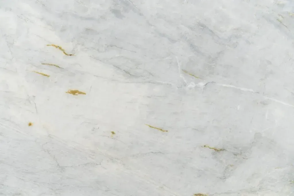 White marble surface with subtle gray veining and small gold flecks.