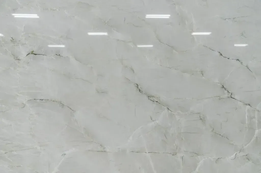 Light gray marble-like wall with subtle veining and reflected ceiling lights