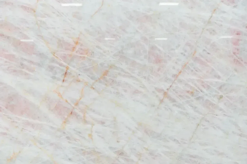 Close-up of a pale white and pink marbled surface with faint orange streaks