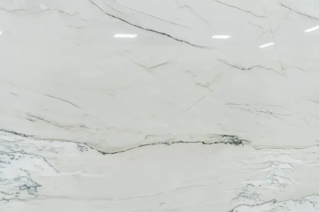 White marble surface with subtle gray veining and polished reflections