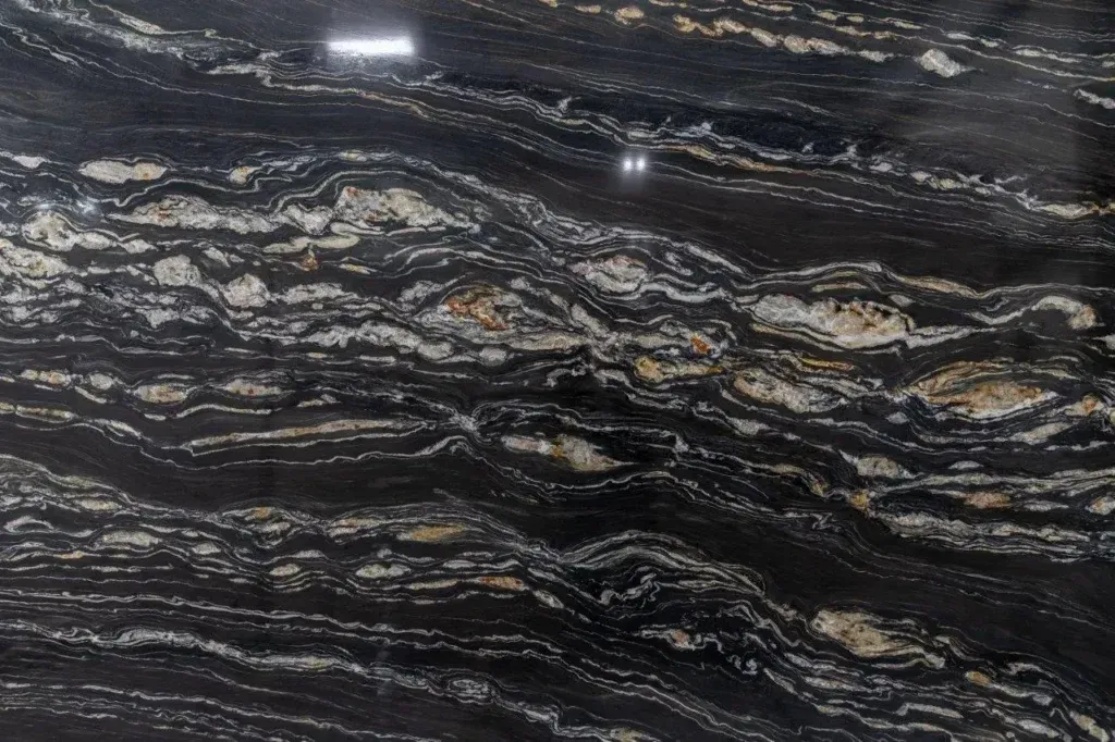 Dark polished stone with white and gray wavy veins and small reflective highlights
