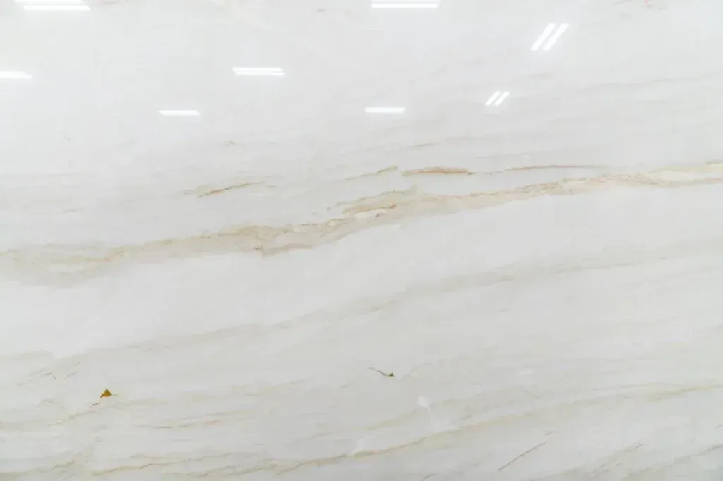 White marble surface with faint beige veining and a few small specks