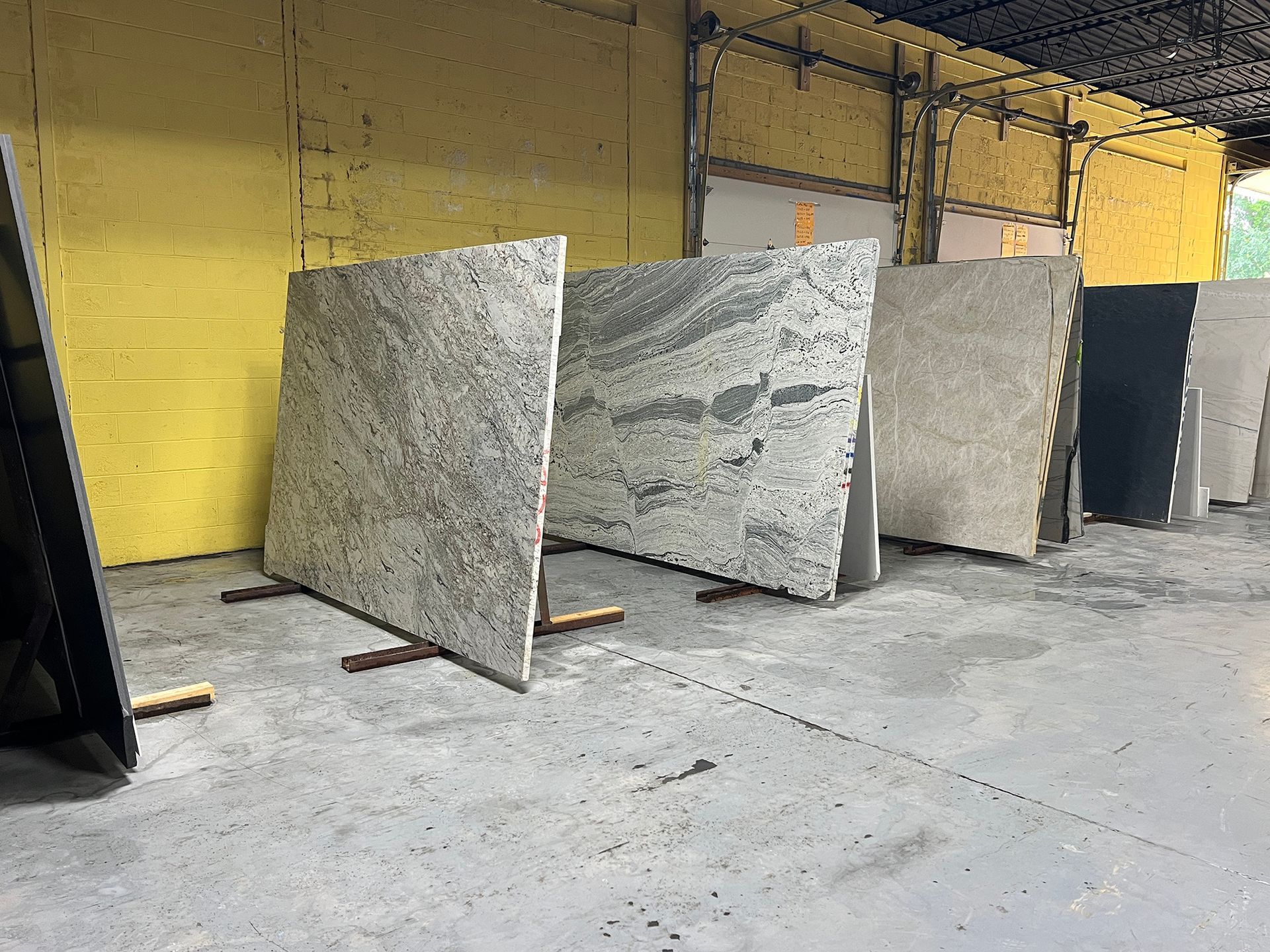 Several large granite slabs leaning upright in an industrial warehouse with yellow walls and a concrete floor