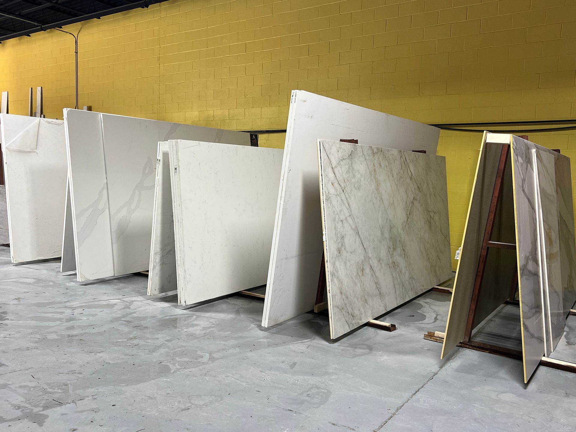 Rows of marble and stone slabs leaning upright in a warehouse or workshop.