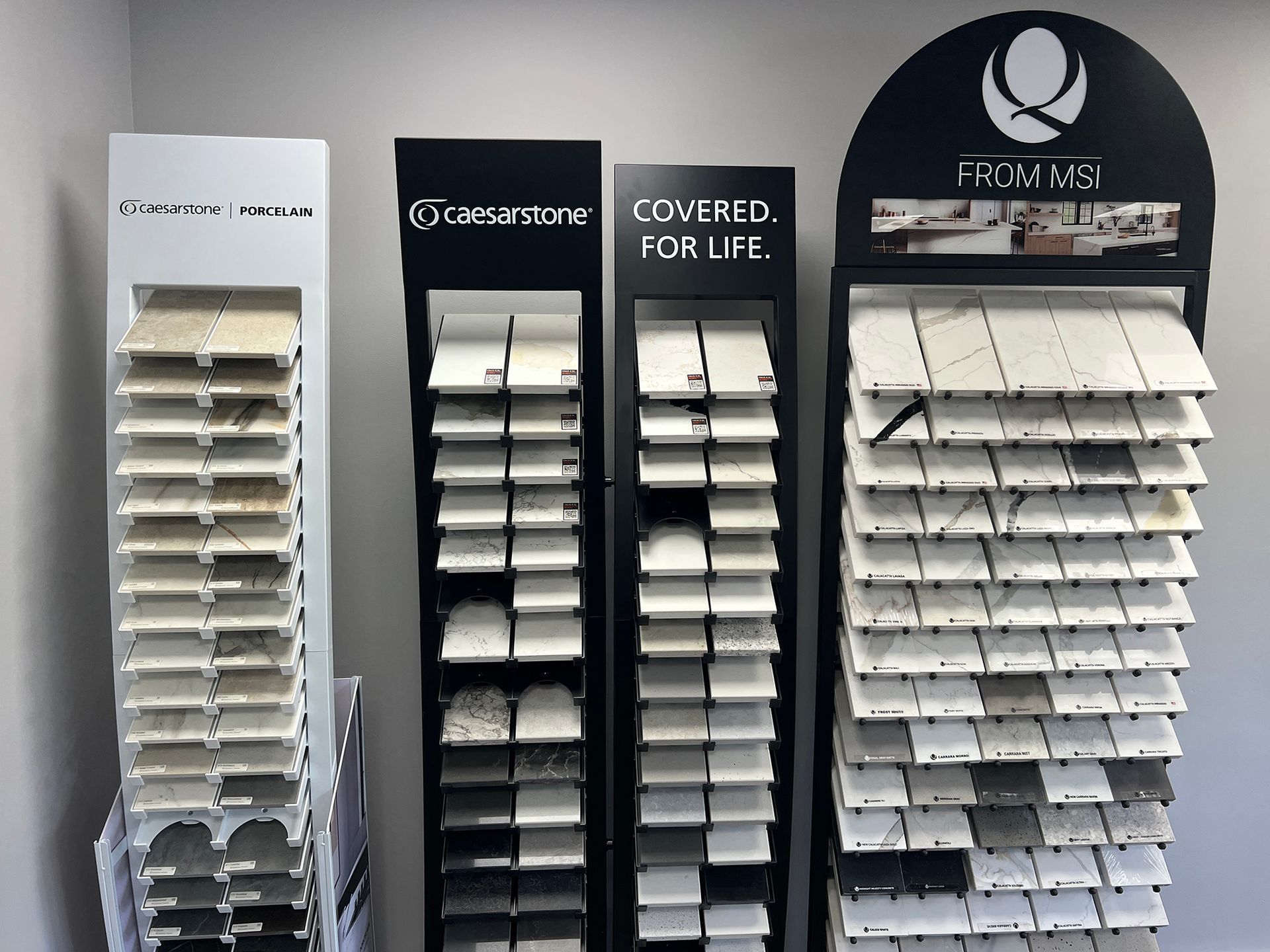Store display of sample blinds and shades in white, gray, and black on vertical racks.