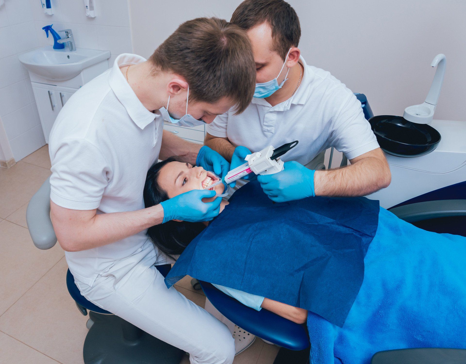 Two dentists are working on a patient 's teeth in a dental office.