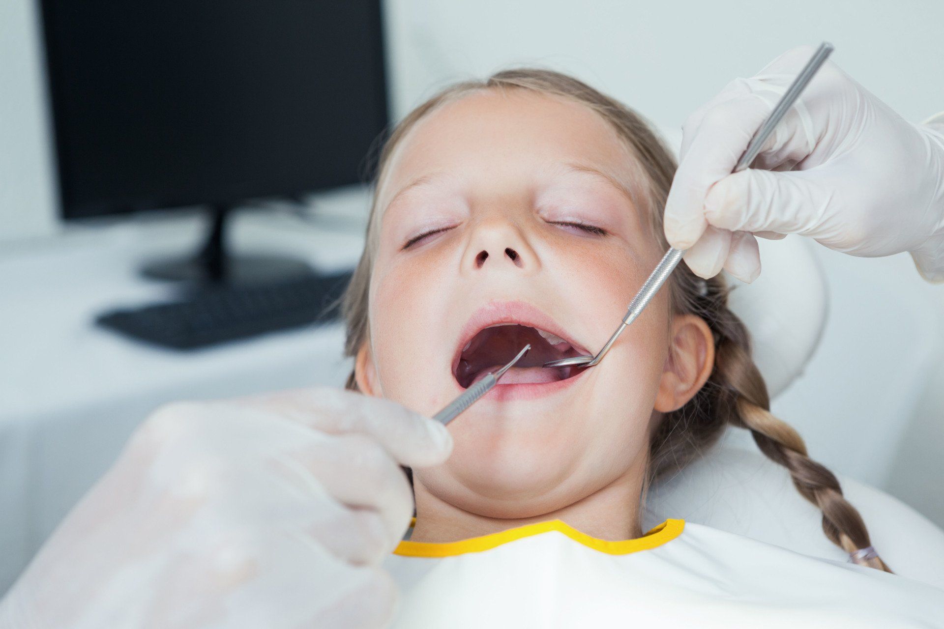 A little girl is getting her teeth examined by a dentist.