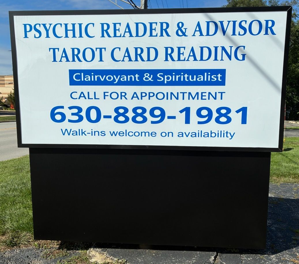 Blue sign for psychic reader and tarot card reading with phone number 630-889-1981 outdoors.