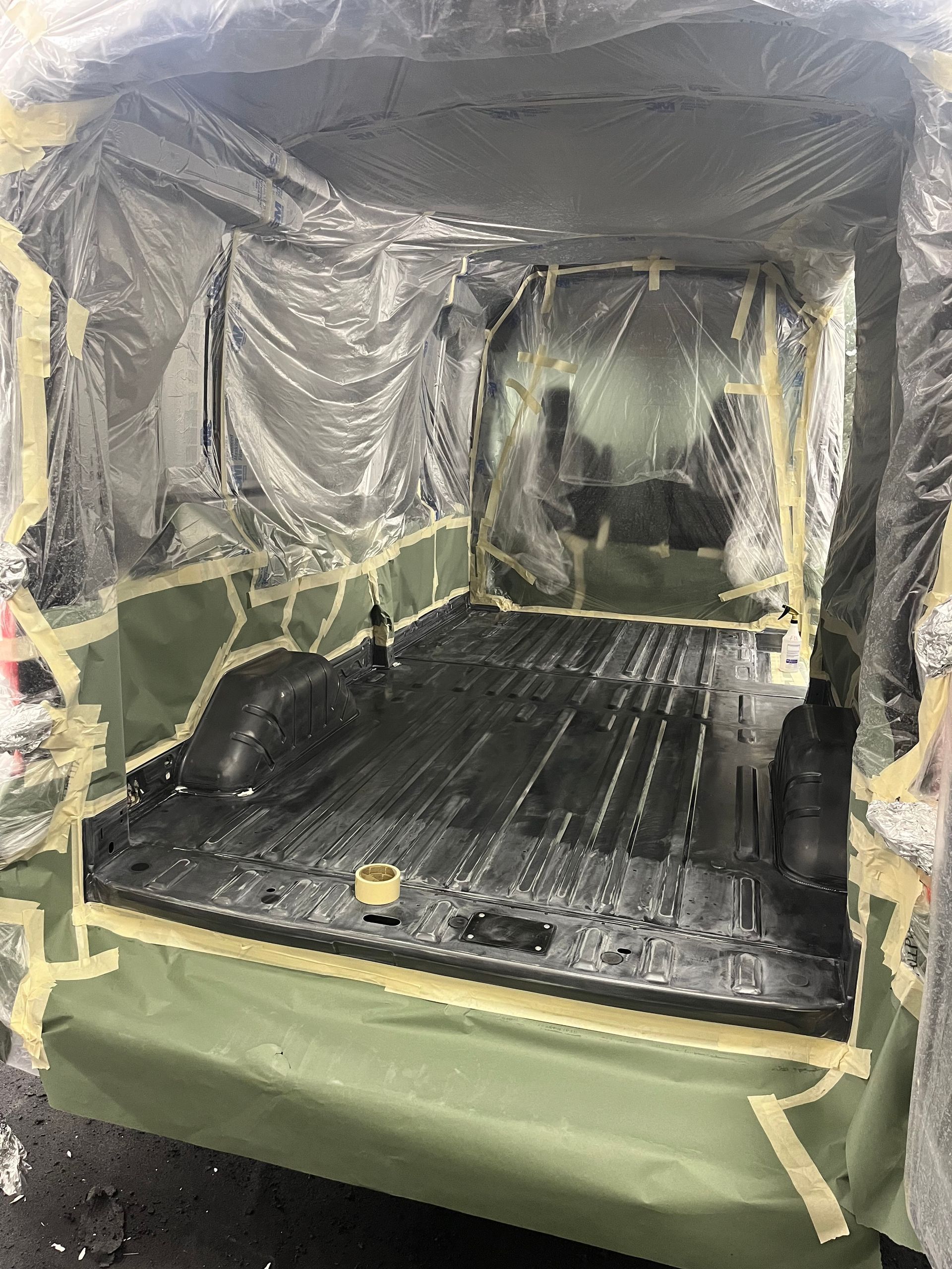 Plastic-covered industrial enclosure with black floor mats and green padded base.